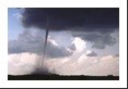 Typical summertime cumulus clouds dot the sky behind this tornado.  The funnel cloud narrows to a pencil while moving very slowly toward the town of Lamar, CO.