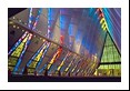 Sunlight filters through stained glass to reach the pews inside a church the shape and feel of a high tech wing (U.S. Air Force Academy)