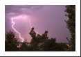 Two cloud-to-ground lightning bolts strike right at dusk; one appears twice as thick as the other.