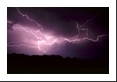 A cloud-to-cloud forked lightning bolt illuminates a pitch black sky.