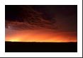 Hoping to photograph a daytime lightning bolt, the sun sets on the horizon while a faint bolt streaks from this cloud to a neighboring cloud.