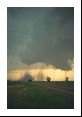 Both dust columns become more visible with an embedded condensation funnel in the foreground tornado. Note more headlights at the end of the road near the second, stronger tornado.